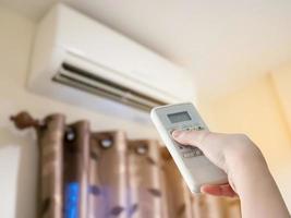 Hand hold remote control directed on the air conditioner photo