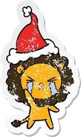distressed sticker cartoon of a crying lion wearing santa hat vector
