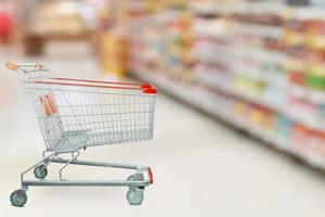 Supermarket aisle with empty shopping cart at grocery store retail business concept photo