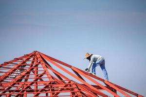 welder workers installing steel frame structure of the house roof at building construction site photo