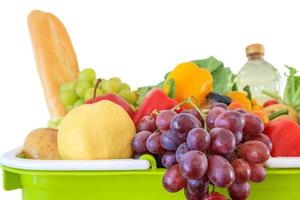 Fresh fruits and vegetables grocery product in green shopping basket isolated on white background photo