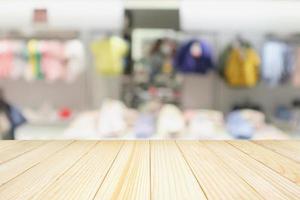 mesa de madera vacía con escaparate de tienda de ropa boutique de moda para niños borrosos en el centro comercial foto