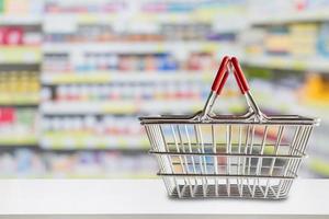 Empty shopping basket on pharmacy drugstore counter with blur shelves of medicine and vitamin supplements background photo