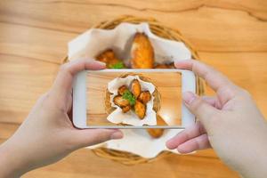 tomando fotos de alitas de pollo calientes y picantes con smartphone