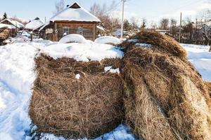 haystack on snow-covered street in village photo