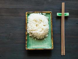 rice on plate and chopstick on rest on brown table photo
