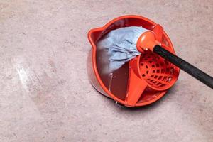 top view of mop in red bucket with dirty water photo