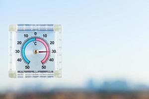 thermometer on home window and blurred skyline photo