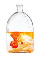 orange watercolour paint dissolves in glass flask photo