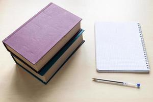 two thick books, pen and blank spiral notebook photo