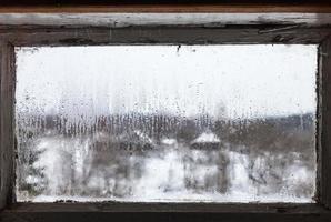 gotas de agua del hielo derretido en la ventana congelada foto