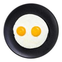 top view of fried eggs on black plate isolated photo