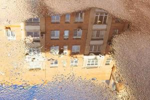 puddle with reflection of apartment house photo