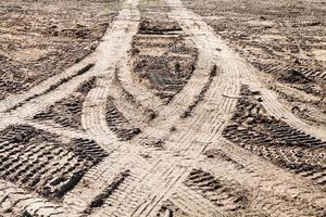 rastros simétricos de neumáticos de coche en campo sucio foto