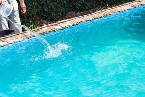 man pours of disinfectant in outdoor swimming pool photo