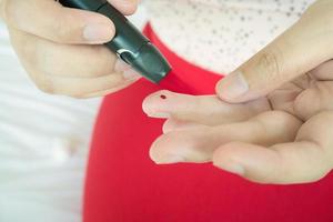 mujer usando lanceta en el dedo, prueba de diabetes foto