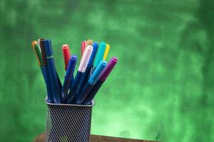 creatividad de un bolígrafo de colores en un estuche con espacio para copiar en un fondo verde borroso foto
