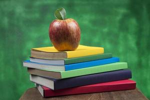 fruta de manzana encima de una pila de libros, en la parte posterior de las clases escolares. foto