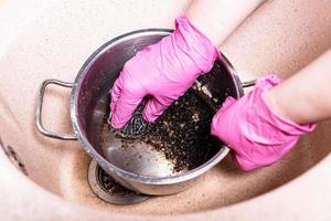 hands wash pan with burnt food with metal sponge photo