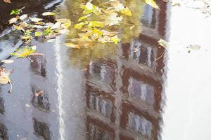 puddle on urban road with reflection of house photo