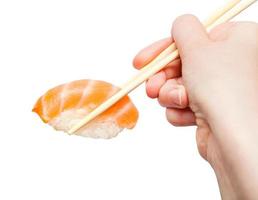 chopsticks hold nigiri sushi with salmon close up photo