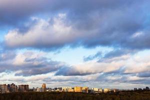 low gray clouds in blue sky over city lit by sun photo