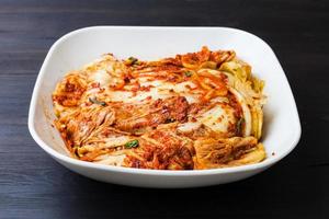 kimchi in white bowl on dark brown wooden board photo