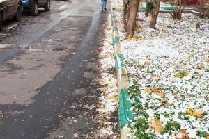 camino y césped cubiertos por la primera nieve en la ciudad foto