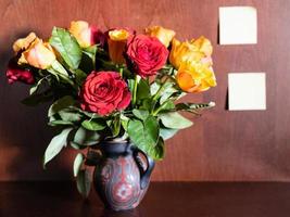 roses in jug and blank notepads on dark brown photo