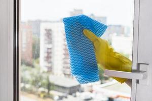 cleaning glass of home window by blue rag photo