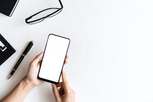 Hand holding empty screen Smart phone and file folder on business desk office with copy space, Top view photo