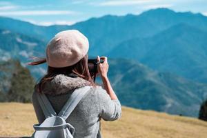 Young woman traveler taking a picture of beautiful landscape photo