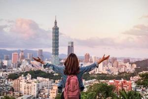 mujer joven viajera mirando un hermoso paisaje urbano al atardecer en taipei, concepto de estilo de vida de viaje foto