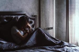 joven solitaria deprimida y estresada sentada en el dormitorio oscuro, concepto de emoción negativa