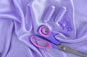 Sewing supplies and accessories for needlework. Spools of thread and other equipment purple colour that uses a tailor to sew clothes on white background. photo