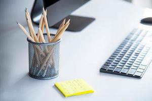 espacio de trabajo moderno con bloc de notas, teclado, computadora o cuaderno y lápices sobre una mesa blanca en una oficina moderna, los accesorios de trabajo para hombres de negocios o diseñadores foto