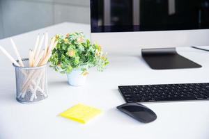 espacio de trabajo moderno con bloc de notas, teclado, computadora o cuaderno y lápices sobre una mesa blanca en una oficina moderna, los accesorios de trabajo para hombres de negocios o diseñadores foto