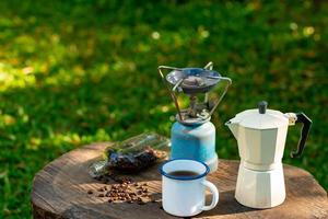 taza de café de esmalte blanco y juego de café matutino en el jardín. foto