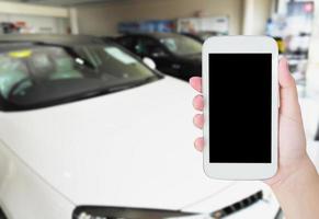 woman hands holding mobile phone with blurred background of new cars photo