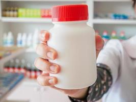 Female pharmacist hold medicine bottle photo