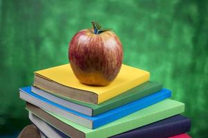 fruta de manzana encima de una pila de libros, en la parte posterior de las clases escolares. foto