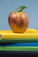 fruta de manzana encima de una pila de libros, en la parte posterior de las clases escolares. foto