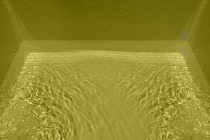 Defocus blurred transparent yellow colored clear calm water surface texture with splashes and bubble. Trendy abstract nature background. Water wave in sunlight with copy space. Yellow water shining. photo
