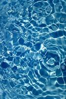 Defocus blurred transparent blue colored clear calm water surface texture with splashes and bubble. Trendy abstract nature background. Water wave in sunlight with copy space. Blue watercolor shining. photo