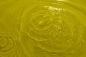 desenfoque textura superficial de agua clara de color amarillo transparente borrosa con salpicaduras y burbujas. fondo de naturaleza abstracta de moda. onda de agua a la luz del sol con espacio de copia. acuarela amarilla brillante. foto