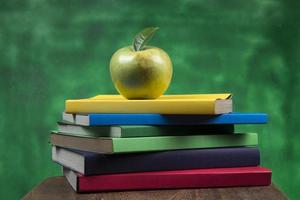 fruta de manzana encima de una pila de libros, en la parte posterior de las clases escolares. foto