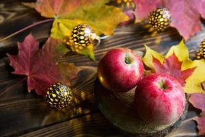 Pink ripe apples on a wooden table with fallen yellow and red maple leaves. Lights of garlands, warm and cozy autumn atmosphere, thanksgiving, harvest festival. Copy space photo