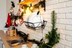 Christmas decor in the kitchen, preparing for the celebration. Lights of garlands, plates, incandescent lamps in loft style. Christmas tree, kitchen utensils. New year's eve, Christmas. House interior photo