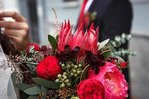 Red wedding bouquet of bride. Floristics, festive decoration of fresh flowers of the ceremony. Symbol of love, roses in pastel shades, succulents in decorative elements, wildflowers. Space for text photo