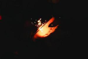 Sparks and light from sparklers in the dark on the palm of a person. Christmas magic, new year's eve, festive background. Space for text photo